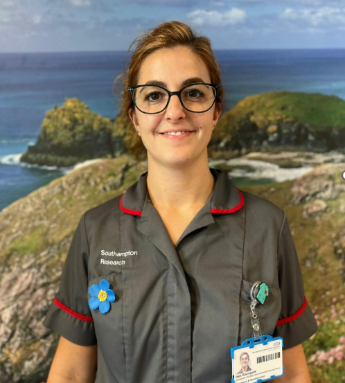 Portrait photo of a young woman wearing nurse scrubs and Alzheimer's Society badge.