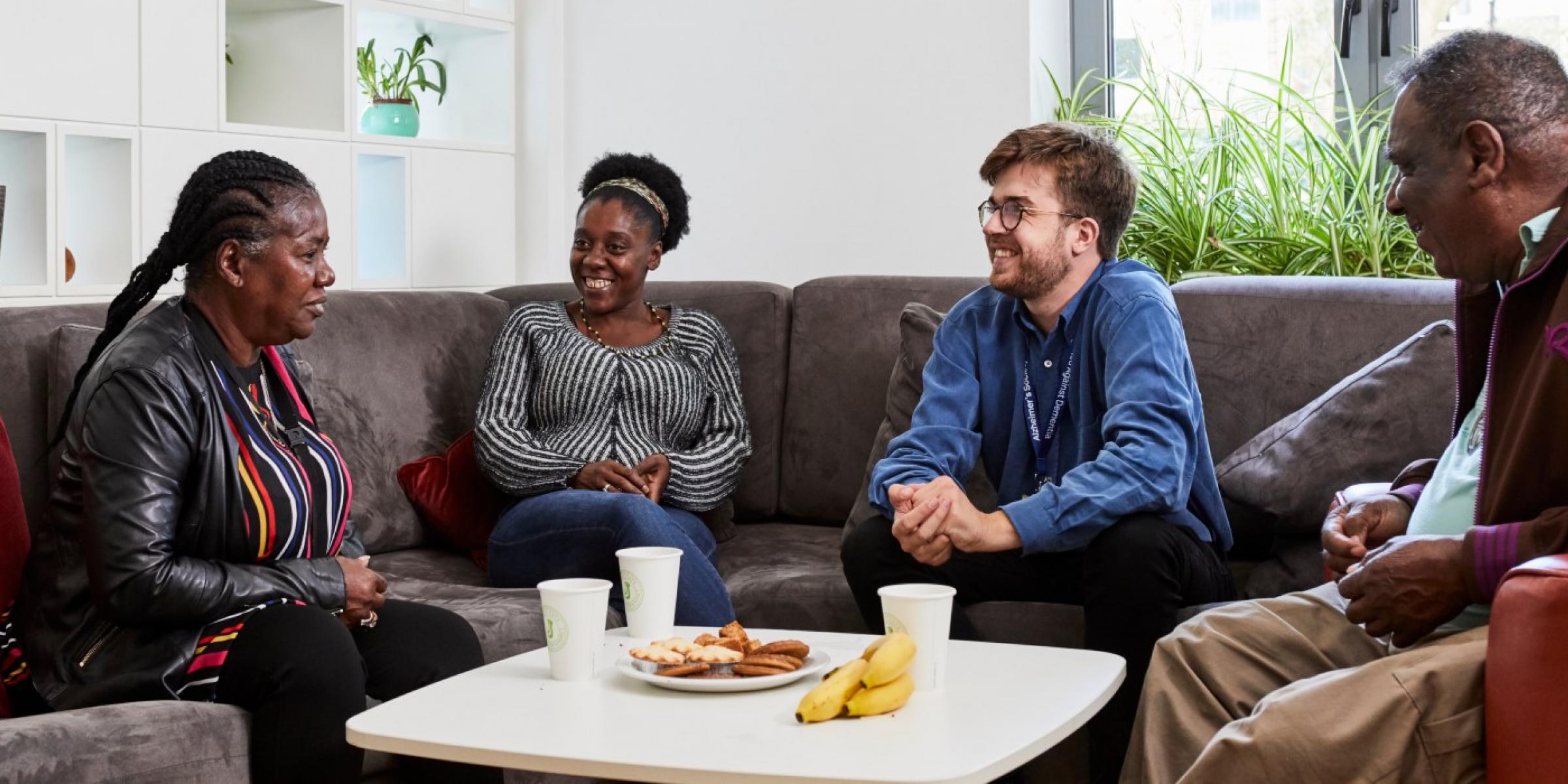 Four people relxaed in conversation on a sofa at a table