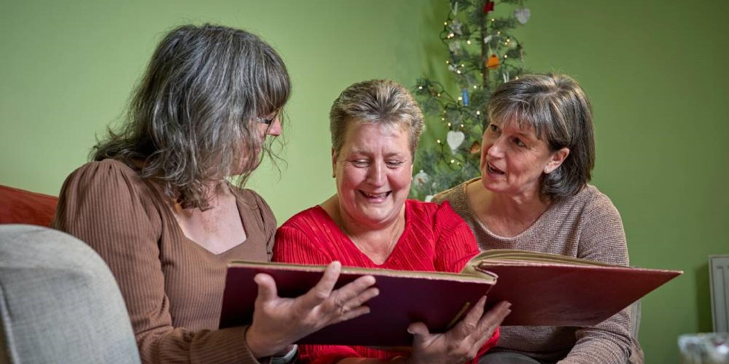 Three sisters looking at a photo album at Christmas