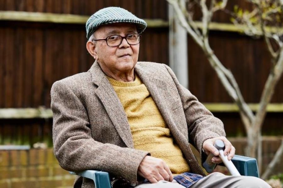 An older man sitting in a chair in his garden