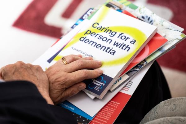 A close up of a pile of Alzheimer's Society information booklets on a person's lap