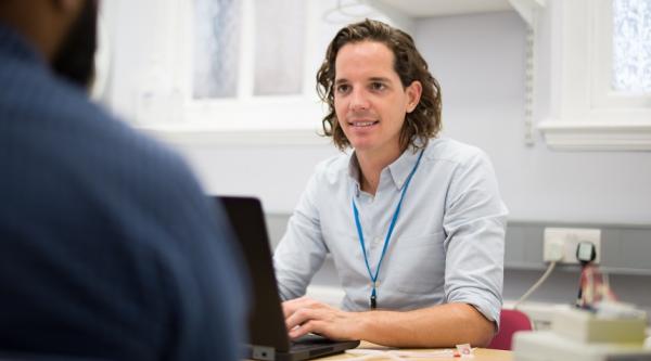 A GP talking to his patient over a desk