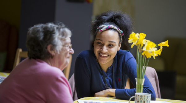 Two women sitting next to each other at a table, laughing