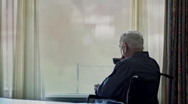 Man on a wheelchair looking out of window
