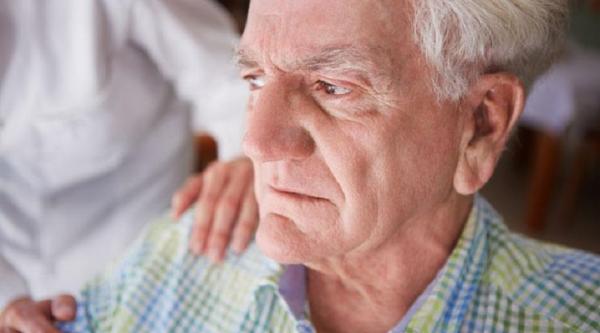 An angry looking man has hands one his shoulder 