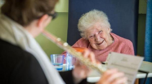 A woman listening to a flute player in hospital