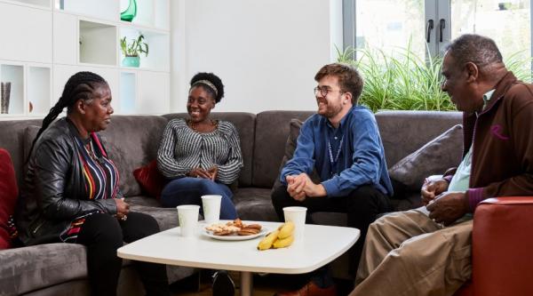 Four people relaxed in conversation on a sofa sitting around a table