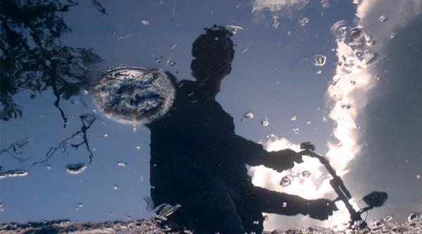 Reflection of someone on a stopped bike in some water