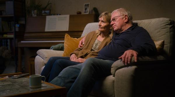 A married couple sitting on a couch at home.