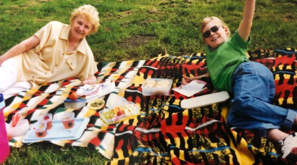 Hannah with her Nanny lying on picnic blankets, smiling and waving