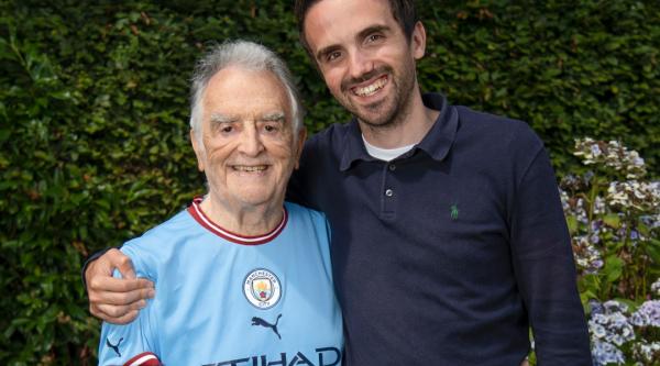 Charlie with his arm round Barry, his grandad, who is wearing a Manchester City football shirt