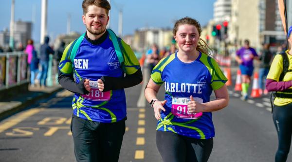 Two people in Alzheimer's Society running shirts jogging through a city