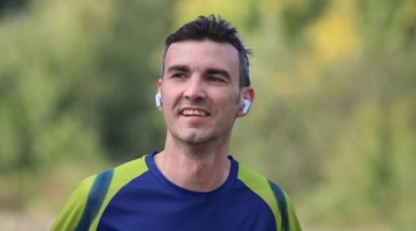 Craig running with headphones in while wearing a blue and yellow t-shirt