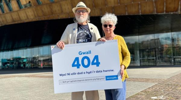 John and Sarah holding a sign in protest