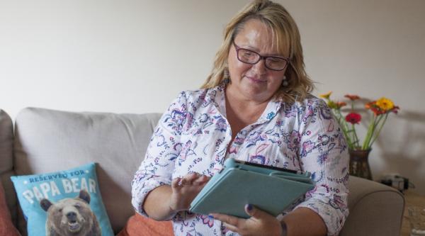 woman sat on the sofa looking at her tablet