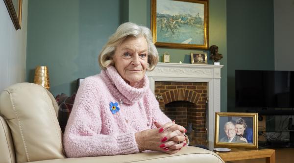 Liz in her living room in front of a photo of her and Eric
