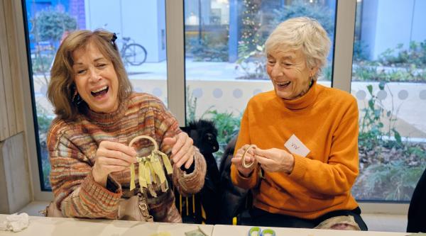 Two women doing crafts at a table and laughing