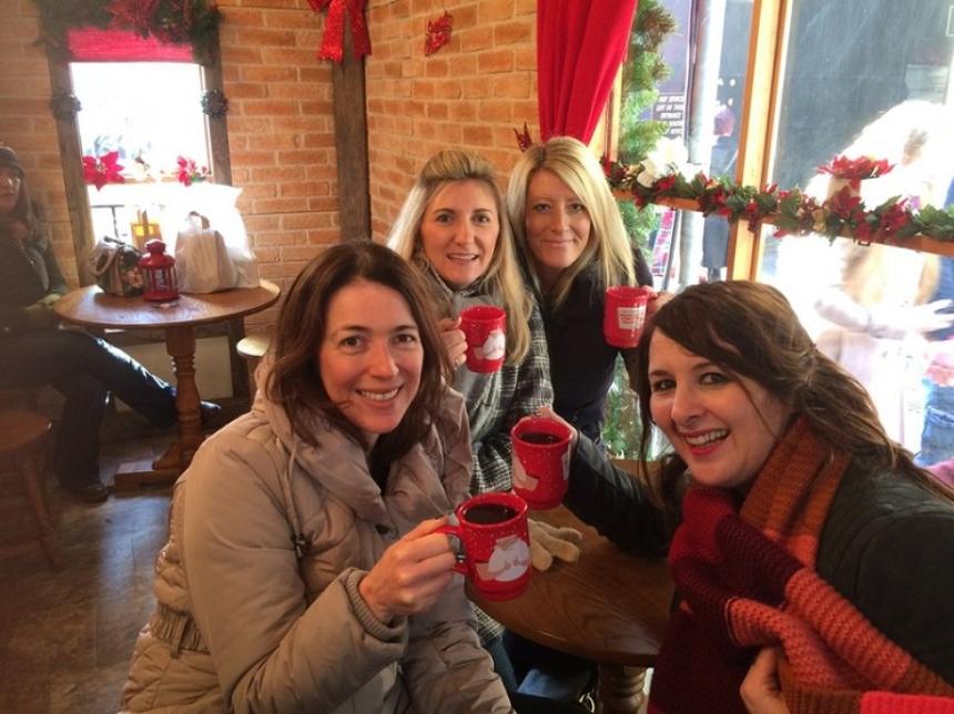 Four women holding coffee cups smiling for a photograph