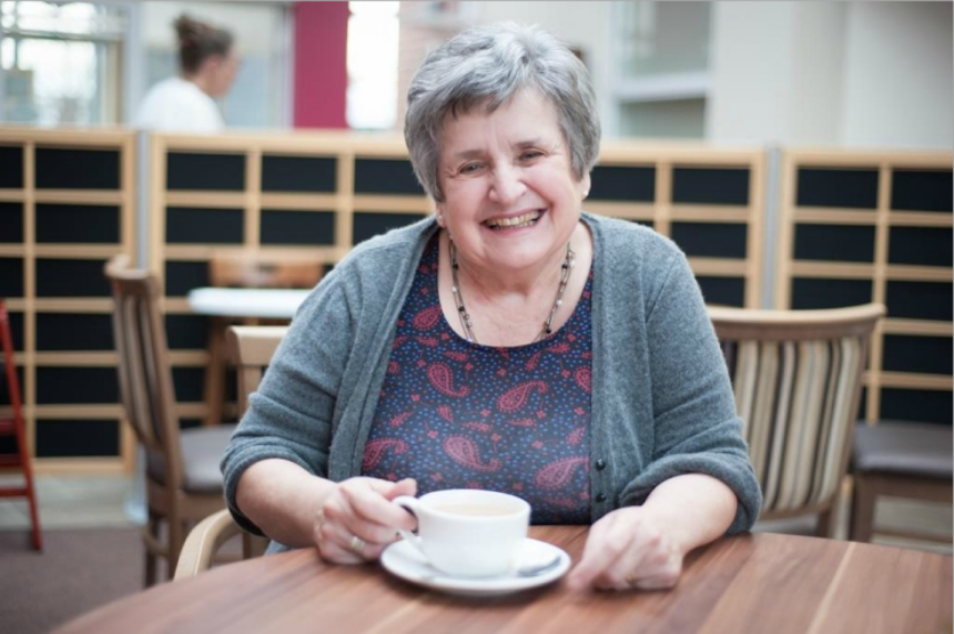 Shelagh sitting at a table with a cup