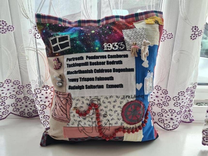The back of the fidget cushion inspired by Ting Ting's granny, featuring stitched names of the places she lived, her birth date and various other colourful objects