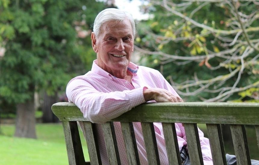 Alan Peacock sat on a bench, smiling towards the camera