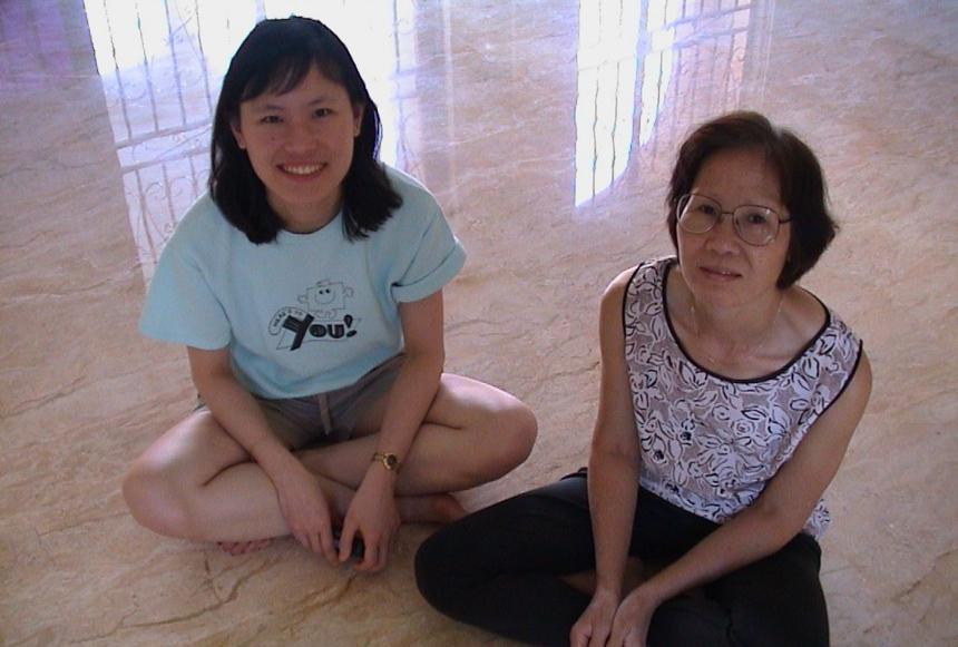 Ai Lyn and Alice both sit cross legged on the floor looking up at the camera