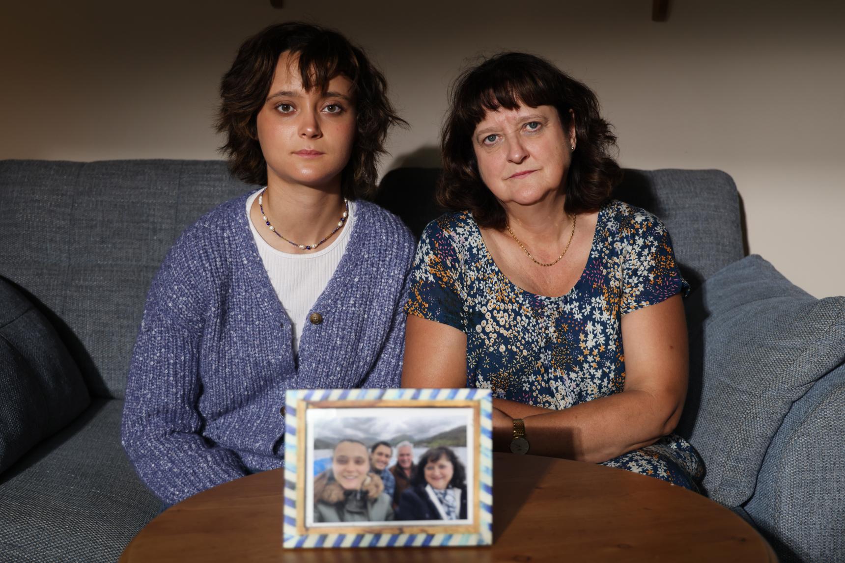 Jane and her child sit on a sofa behind a family photo