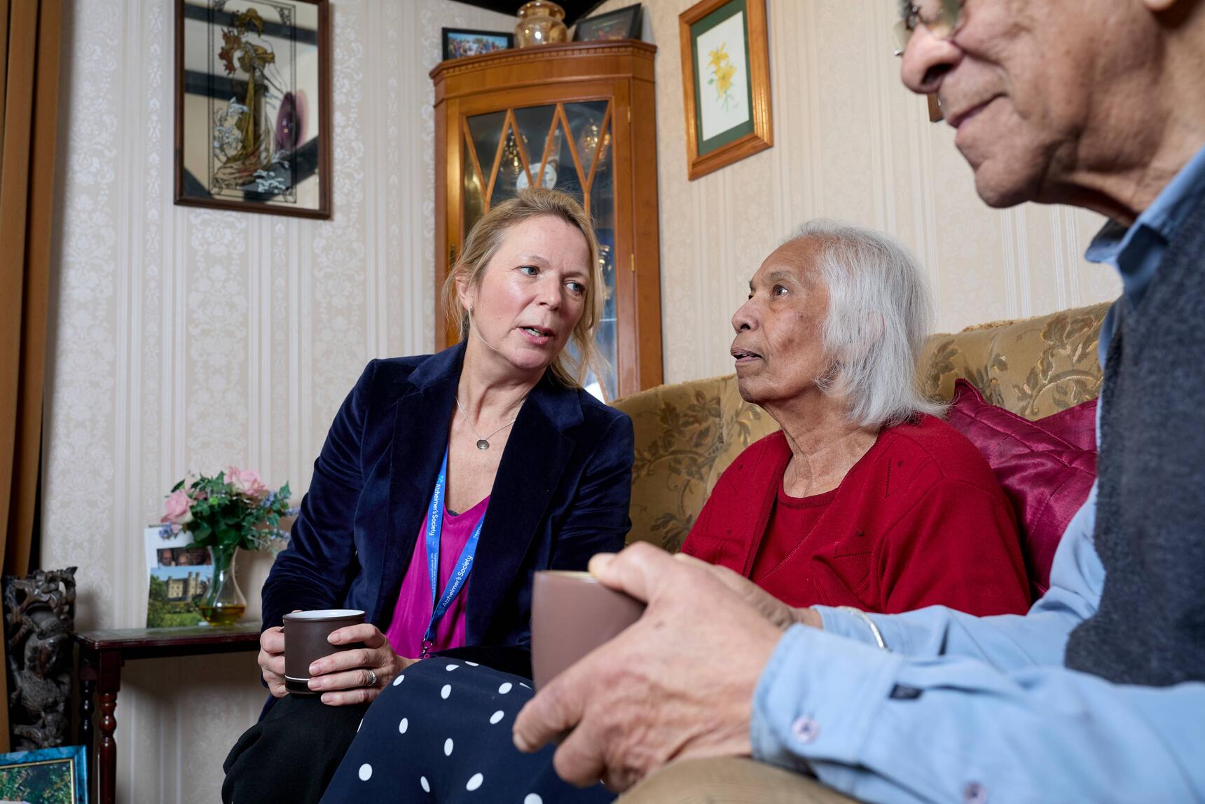 Couple with someone from Alzheimer's Society, sat on a sofa in a living room