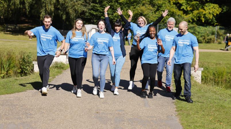 Group pf people wearing blue Memory Walk t-shirts, smiling with their arms in the air