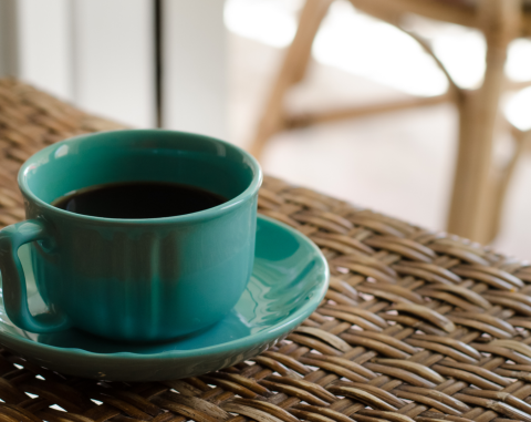 A green coffee mug on a brown wicker table