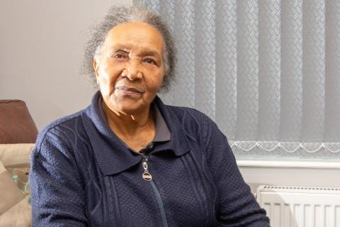 A woman sitting in a chair in her living room, smiling