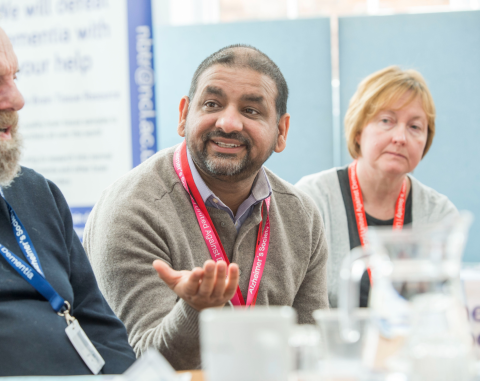 A person talking around a table wearing Alzheimer's Society lanyards