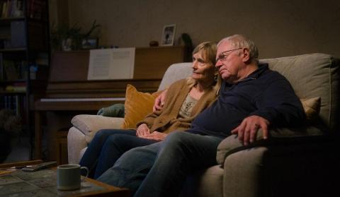 A couple sit on a sofa