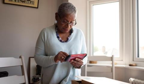 A woman stood up in her living room looking at her phone