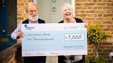 A couple holding a giant cheque for £1000