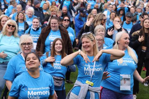 Crowd of people in blue Memory Walk t-shirts dancing and smiling.