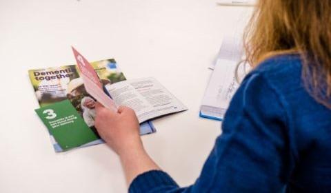 A woman reads through a selection of paper booklets