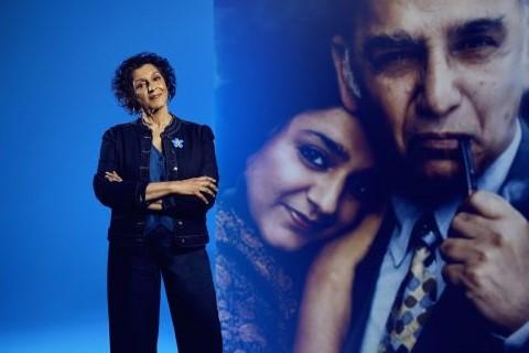 A woman stands in front of an enlarged photo of her father