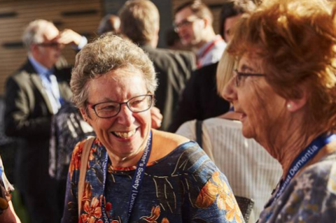 A woman wearing an Alzheimer's Society lanyard smiles at her companion 