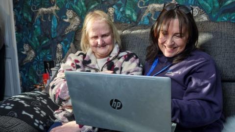 Two people use a laptop together