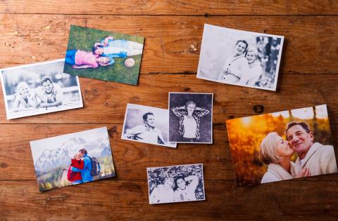 Scattered photographs laid out on a wooden table.